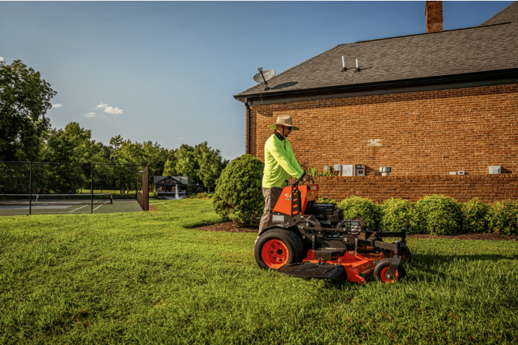 Landscaper mowing lawn with Stand-On Mower