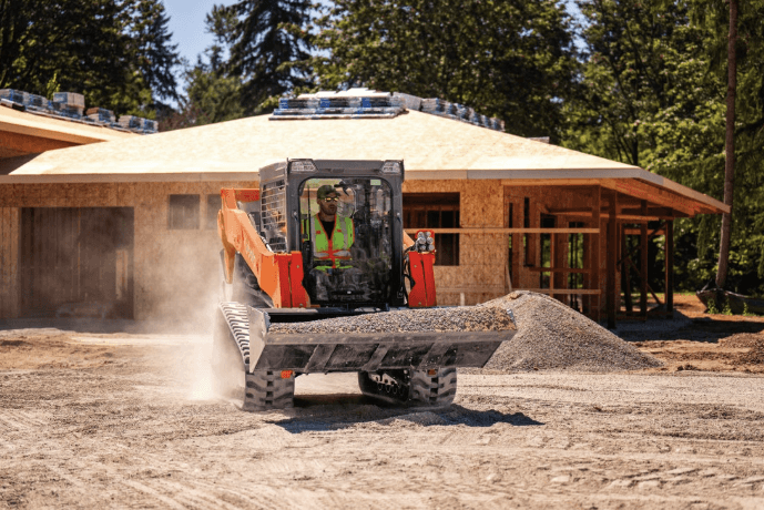 Track loader moving material with bucket attachment