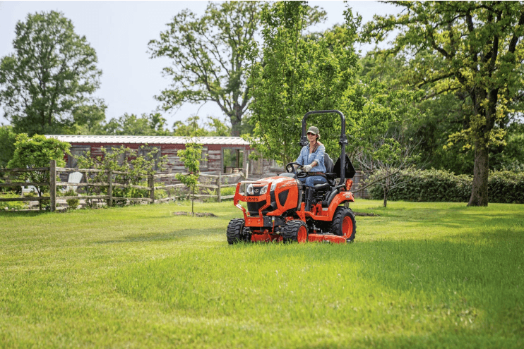 Woman using Sub-Compact Tractor to mow yard